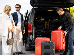 The nose of a plane visible through floor to ceiling windows in an airport, with seats inside in the foreground