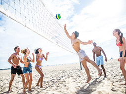 A group of men playing volleyball on the beach in Valencia with Stag Hen Spain
