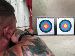 A man aiming a bow at a target at archery in Torquay
