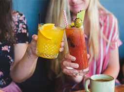 Two woman clinking cocktail glasses at a bottomless brunch in Benidorm