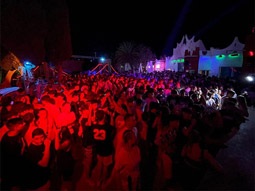 A group of people dancing in neon lights by the beach at KU Club in Benidorm