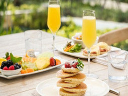A table with brunch items on and a glass of alcohol in a champagne flute