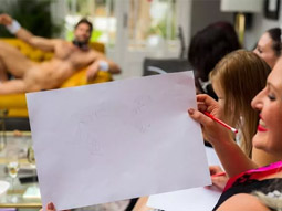 A girl holding her drawing of a nude man up at Mobile Nude Life Drawing