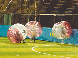 Three people in large inflatable bubbles playing bubble football in Lisbon