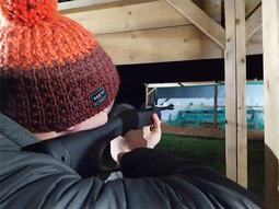Someone aiming an air rifle at a target in the dark