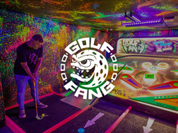Someone playing golf with neon lights around the room at Big Fang Crazy Golf