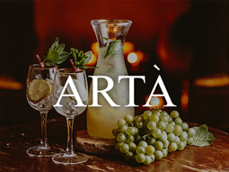 Cocktails on a table with grapes and a full bottle at Arta in Glasgow