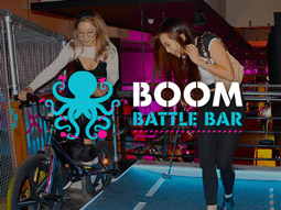 A girl on a bike and a woman with a golf club at crazier golf at Boom Battle Bar