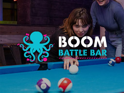 A girl playing American pool at Boom Battle Bar