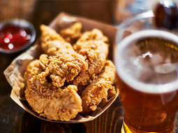 A plate of wings next to a pint of beer on a wooden board in Algarve