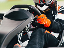 Someone racing a go kart outside with a helmet and gloves on