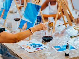 A group of people painting while drinking glasses of wine 