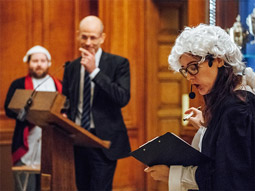 A woman dressed up in a judge outfit with a wig at a Comedy Court Room Roast