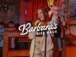 A group of people watching someone perform karaoke at Heidi's Bier Bar