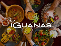 Different food dishes and cocktails on a table with the Las Iguanas logo overlayed