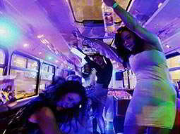 A Dublin hen group dancing inside a party bus under blue and purple lights