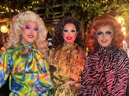 Three drag queens smiling for a photo at an afternoon drag show in Liverpool