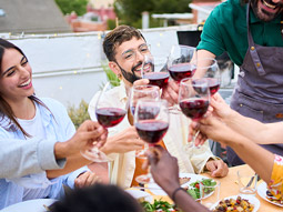 People clinking glasses of wine and smiling at a dinner