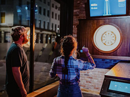 Guy teaching girl how to play darts