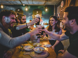 Three men and a woman having some Guinness and food in a bar 