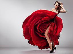 A woman holding up a red flamenco dress and showing her legs