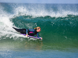 A woman bodyboarding a wave in Newquay