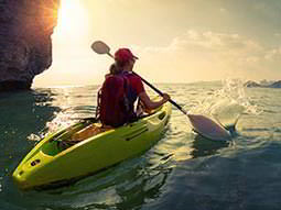 A woman in a yellow kayak paddles through still water