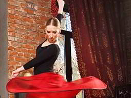 A woman in a floaty red skirt, spinning whilst dancing flamenco 