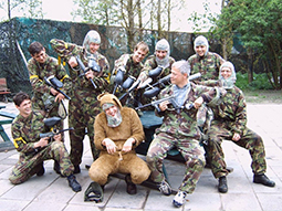 A group of men aiming paintball guns at a main dressed in a costume