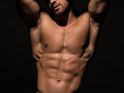 A semi-naked man posing against a black background