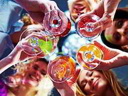 A photograph taken from below, of five friends holding their glasses together 
