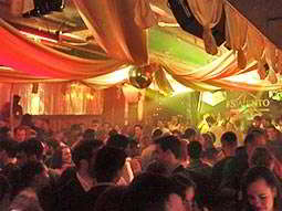 A view over a filled dance floor with white canvas above, and orange lighting