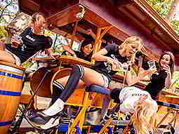 Some girls on a beer bike outdoors, drinking beer 