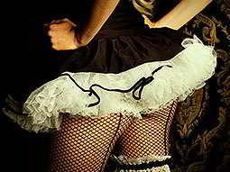 The back of a woman in a black and white tutu, corset and fish nets