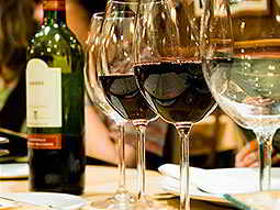 Close up on two bottles of red wine and white wine in the foreground, with half a bottle of red in the background