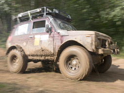 A 4x4 driving through the wilderness, kicking up mud as it drives