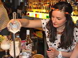 A woman pouring a cocktail into a glass