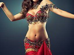 A woman dressed in a red Bollywood outfit, dancing 