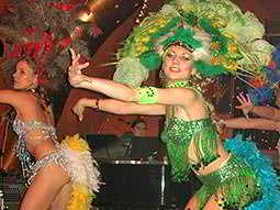 Two women dressed in carnival clothing, dancing in a small venue