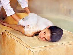 A woman lying forwards on a bed receieving a back massage