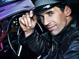 A chauffer tipping his cap, whilst sitting at the steering wheel