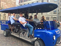 A group of people sat on a beer bike on a road