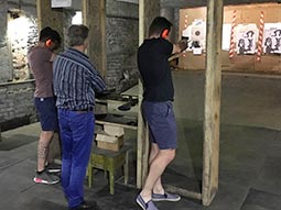 Two men with an instructor, aiming guns at a target