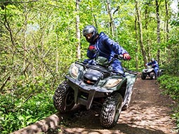 A man on a quad bike driving with another man behind him
