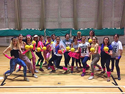 A person reaching for a pink glitter dodgeball on a court