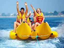 Some people sitting on a banana boat, riding across the water
