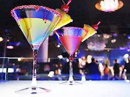 Two cocktails in martini glasses with a slice of pineapple on the side of the glass