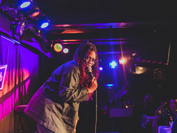 A woman performing on stage at a comedy club
