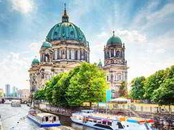 A grand building in Berlin, with two boats in the foreground in the river
