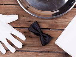 A glove and a bow tie on a wooden table 